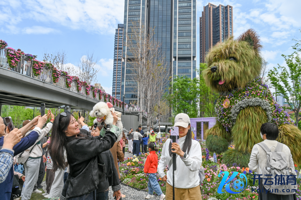 4月18日，上海苏河湾，市民举着小狗和“松驰小狗”花艺雕刻合影。倾盆新闻记者 朱伟辉 图